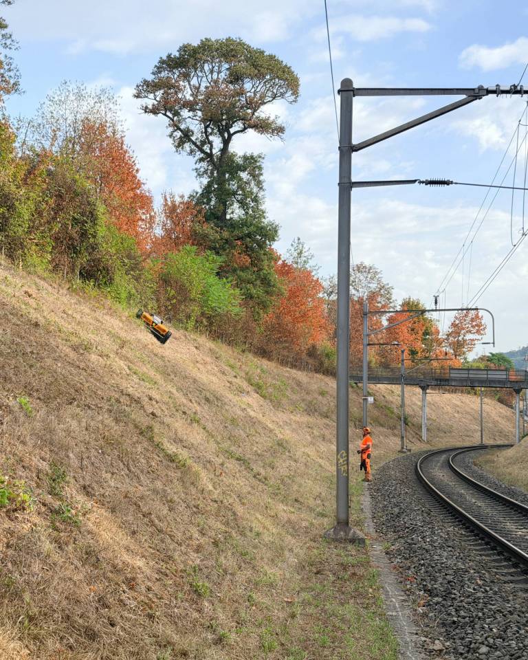 AS 990 Tahr RC und Bedienperson beim Mähen entlang einer kurvigen SBB-Bahnstrecke